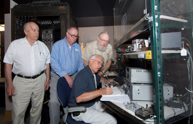 Group of men huddled around a Ham Radio